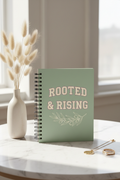 ROOTED & RISING sage green spiral notebook upright on marble with pampas grass and gold rings