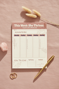 This Week She Thrives A5 weekly planner notepad flat lay showing 7-day structured layout